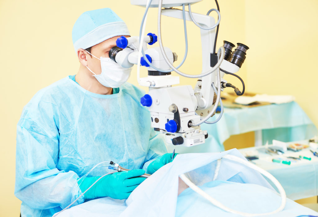 Surgeon in blue and mask at work operating over yellow walls